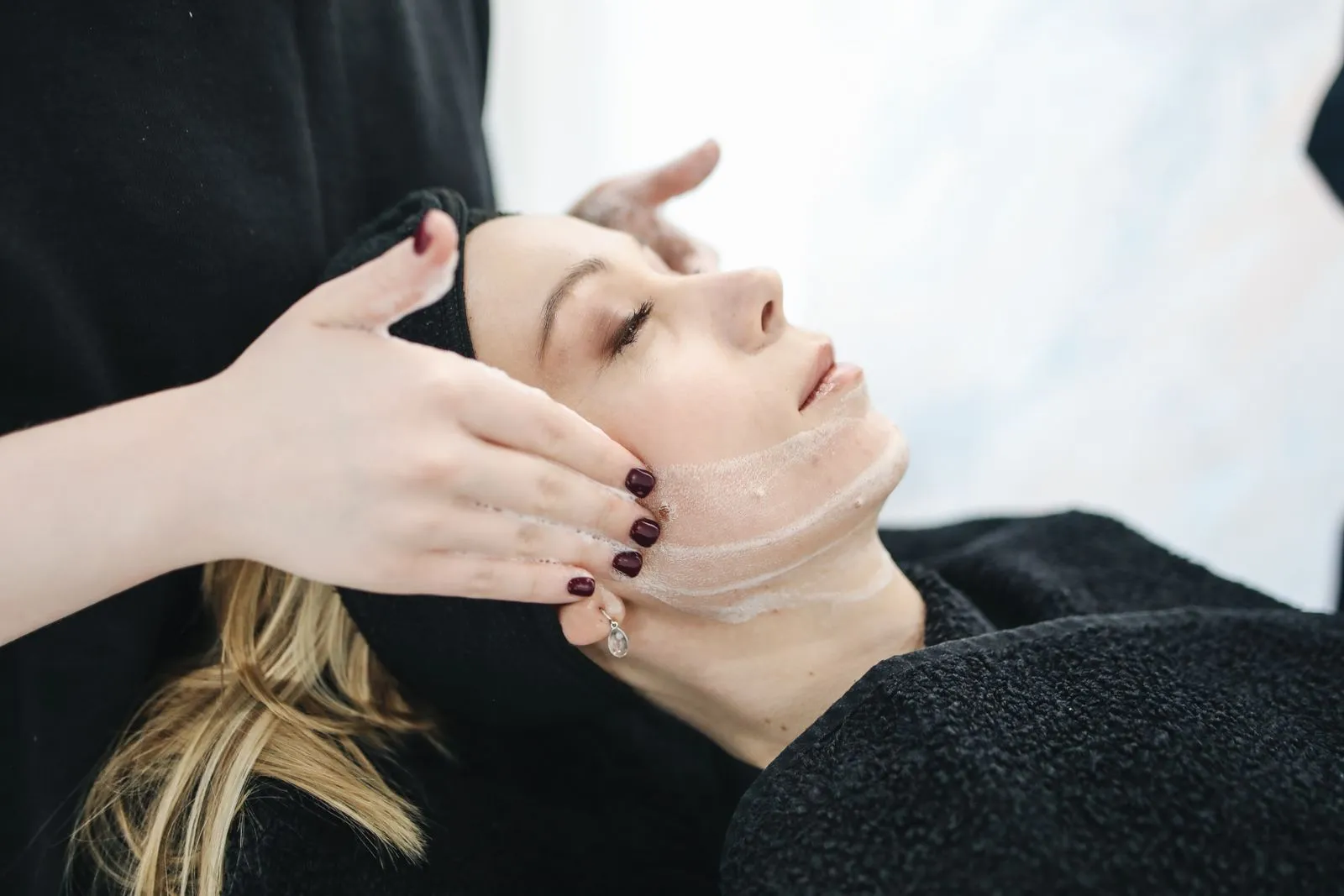 An esthetician massaging a client’s face during a facial